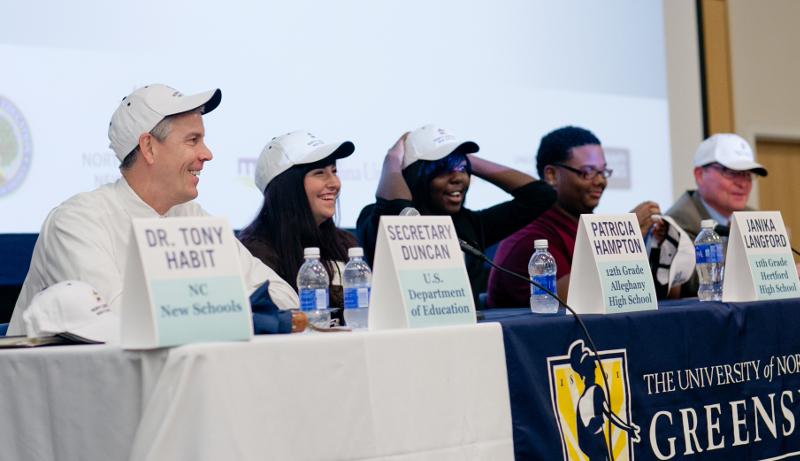 U.S. Secretary of Education Arne Duncan tries on his NC New Schools hat along with panelists during the grant announcement at UNCG.